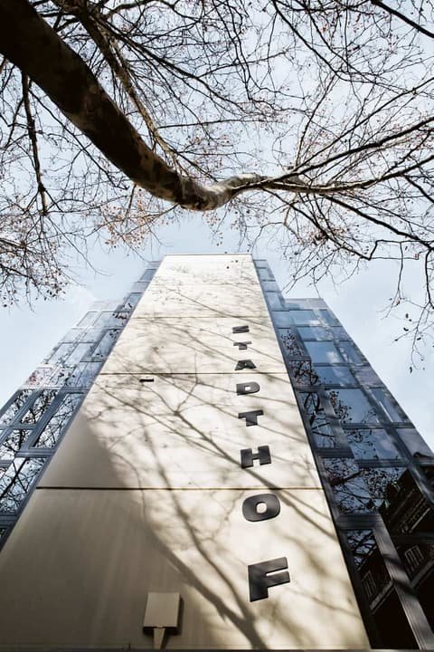 View up the Stadthof facade with the vertical lettering, framed by bare tree branches