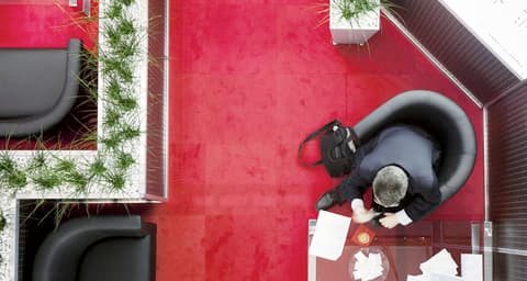 View from above of a person in a black armchair on a red carpet