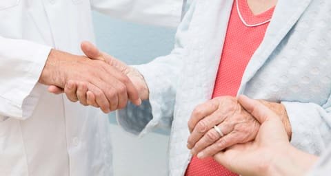 Close-up of a handshake between a person in a white coat and another person