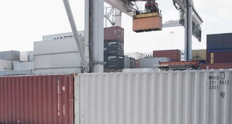 Container terminal with stacked containers and a crane lifting a container