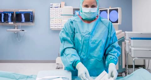 Theatre nurse in green surgical gown and mask in an operating theatre at Stadtspital Waid