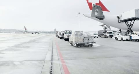 Airport apron with ground vehicles and the red tail of an aircraft