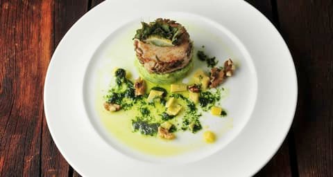 Plated dish with herb sauce on a white plate on a dark wooden table, Klaus Leuenberger Speisewerk