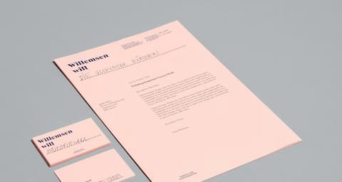 Pale pink letterhead and business cards on a grey surface
