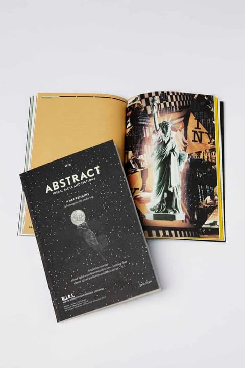 Black cover of the W.I.R.E. magazine Abstract lying on an open issue with a yellow page