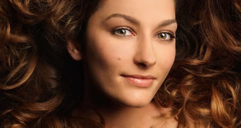 Portrait of a woman with long auburn curls, cover image of the HairMail magazine for Bayer