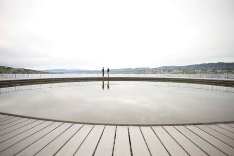 Two people standing on a wooden lakeside platform under an overcast sky, photo shoot for Brunner Strategy