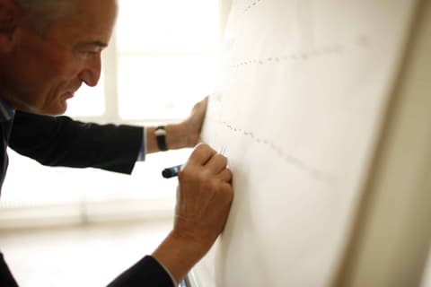 Man writing with a marker on a large sheet of paper on the wall, Brunner Strategy photo shoot
