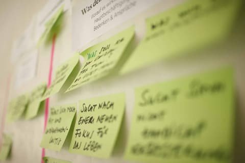 Green sticky notes with handwritten keywords on a wall, Brunner Strategy workshop
