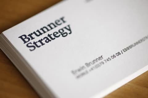 Close-up of a stack of Brunner Strategy business cards on a wooden table