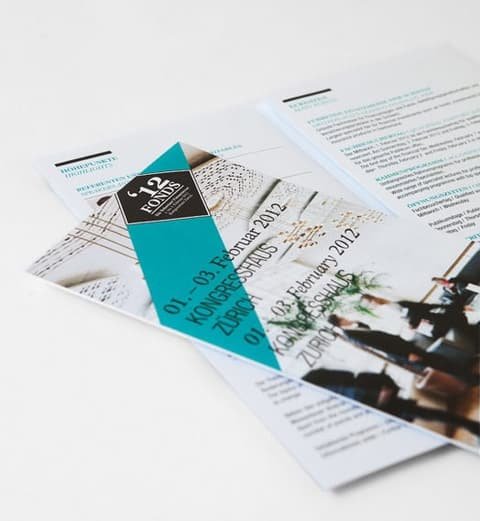 Fondsmesse Schweiz flyers fanned out, with the diamond logo and a turquoise diagonal ribbon