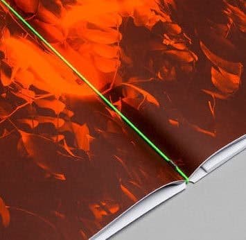 Close-up of the Dayglo poster on fluorescent orange paper with a green line running across the fold