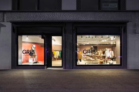 Gris shop front at night with the logo on the lit display windows