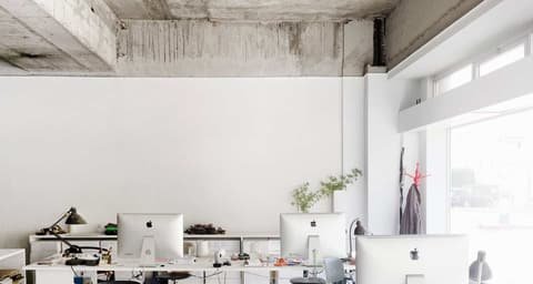 Varese Corridor studio: desks with computer screens beneath a raw concrete ceiling