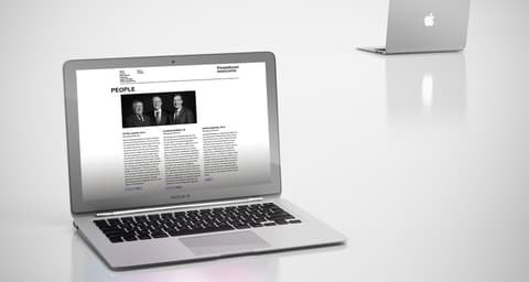 PrimeMover Associates website with partner portraits on a laptop