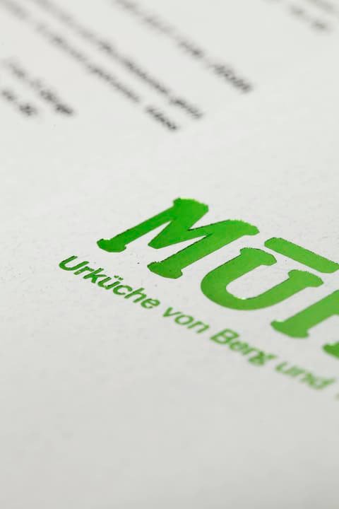 Close-up of the green Mühle logo printed on paper