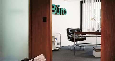 Key visual for Stadthof by EMB Immobilien: office with desk and leather chair between wood panelling, the word Büro above