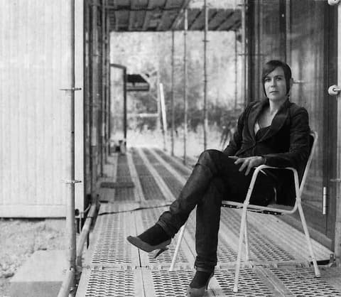 Alejandra Lauper seated on a chair on a covered walkway, black-and-white portrait